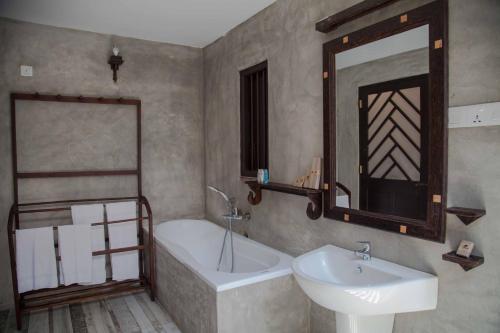 a bathroom with a sink and a tub and a mirror at Villa Pinnawala in Pinnawala