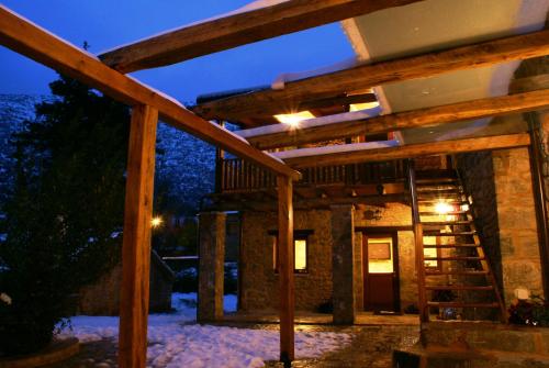 una casa con terraza de madera en la nieve por la noche en Argyriou Wine Tasting Guest House, en Polydrosos