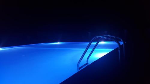 a swimming pool with blue lights in the dark at Hotel Porto Potha in Telendos
