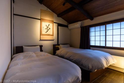two beds in a room with a window at Kyoto Gojo Samurai Machiya in Kyoto