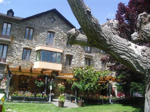 a large stone building with a large tree at Hostal Vall D'Aneu by Arcas & Sambola in Esterri d'Àneu