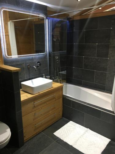 une salle de bain avec un lavabo, une baignoire et un miroir dans l'établissement La Para, à Chamonix-Mont-Blanc