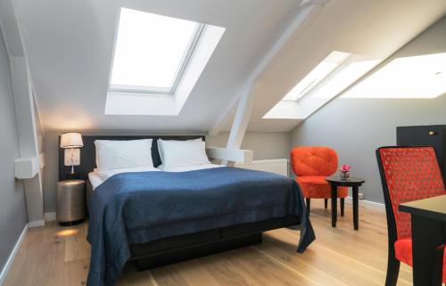 a bedroom with a bed and a red chair at Thon Hotel Spectrum in Oslo