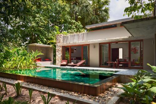 a house with a swimming pool in front of a house at Templation Hotel in Siem Reap