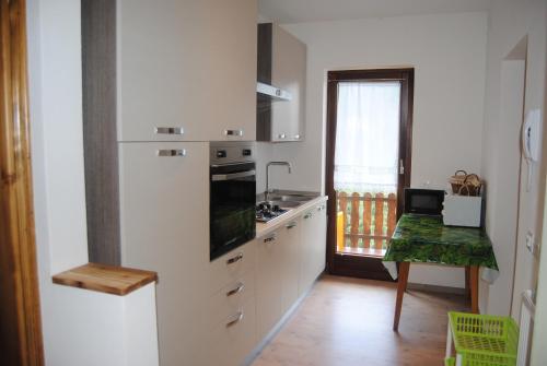 a kitchen with white cabinets and a table and a window at Appartamento Rustico in Candide