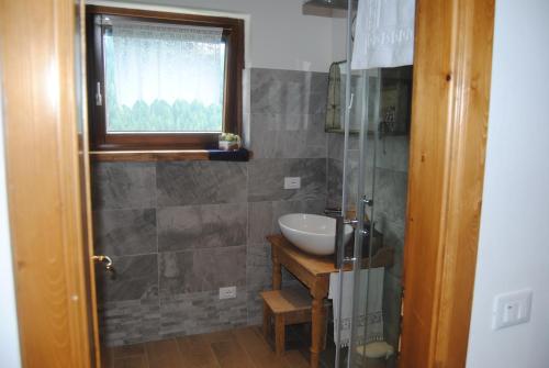 a bathroom with a sink and a mirror and a window at Appartamento Rustico in Candide