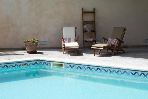 - une piscine avec 2 chaises et une table dans l'établissement la Palisse, à Peaugres