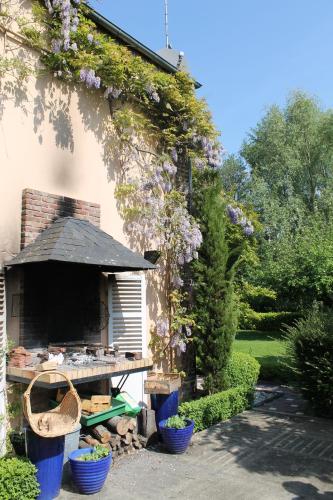 a garden with a table and purple flowers on a building at Comme une parenthèse au coeur des hortillonnages in Amiens