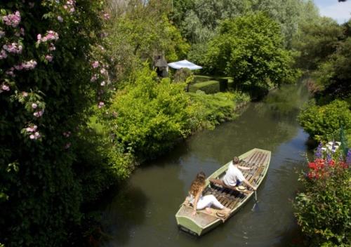 two people and a dog in a boat on a river at Comme une parenthèse au coeur des hortillonnages in Amiens