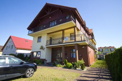 a house with a car parked in front of it at Villa Tropikana in Łeba