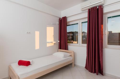 a bedroom with a bed with red curtains and a window at Hostel Free Bird in Dubrovnik