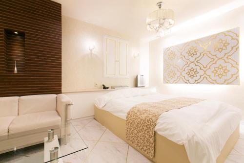 a white bedroom with a bed and a couch at Hotel Atlantis Higashi Osaka (Adult Only) in Osaka