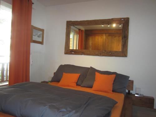 クランにあるMesnil 18のベッドルーム1室(オレンジ色の枕と鏡付きのベッド1台付)