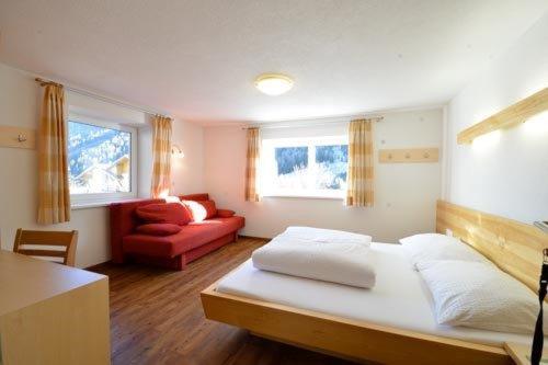 a bedroom with a bed and a red couch at Apart Muntane in Ischgl