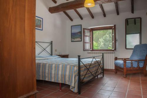 1 dormitorio con 1 cama, 1 silla y 1 ventana en Podere i Giganti, en Scarlino