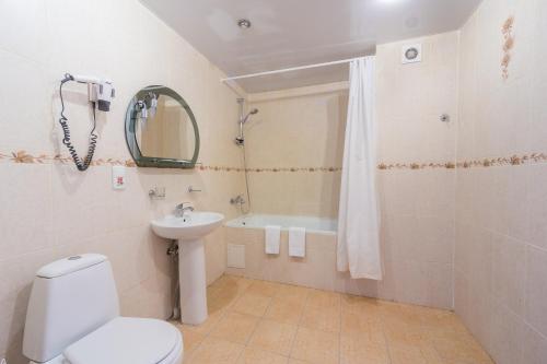 a bathroom with a toilet and a sink and a tub at Hotel Sportivnaya in Simferopol