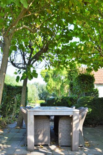 a picnic table with chairs under a tree at Het Zoete Pèèrd in Groede