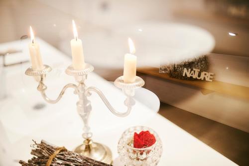 a table with three candles and a bowl with a rose at Landgasthaus Helpfauer Hof in Uttendorf