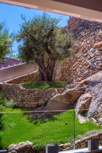 a tree in front of a stone wall at Domu Simius Life Style Hotel in Villasimius