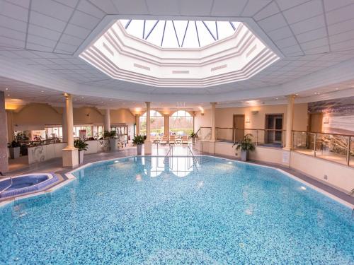 a large swimming pool in a building with a skylight at The Culloden Estate and Spa in Belfast