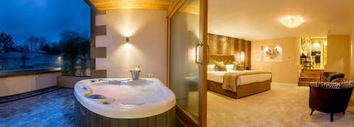 a bathroom with a bath tub and a bedroom at Applegarth Villa Hotel & Restaurant (Adult Only) in Windermere