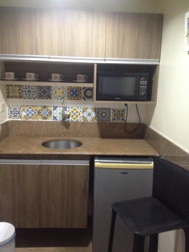 a small kitchen with a sink and a microwave at Victory Business Flat in João Pessoa