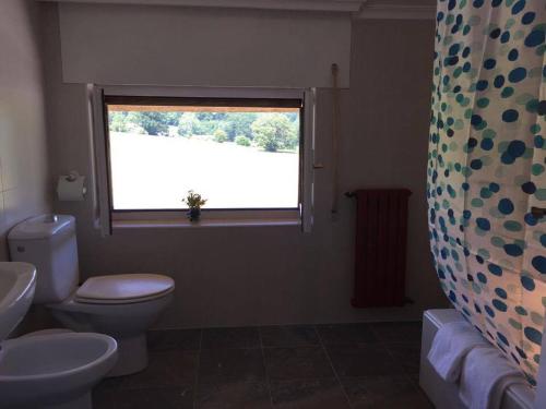 a bathroom with a toilet and a window at Hostal El Paso in Beranga