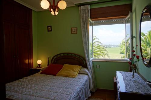 a bedroom with green walls and a bed with a window at Casa Gayol in El Franco