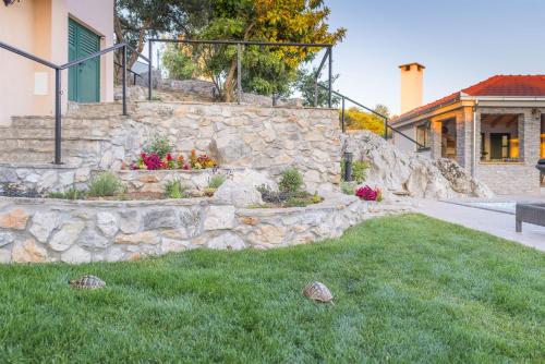 a stone retaining wall in front of a house at Villa Boulder in Okrug Donji