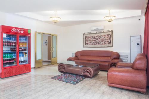 a living room with a cocacola soda machine and a couch at Hotel Alma Ata in Zhosaly