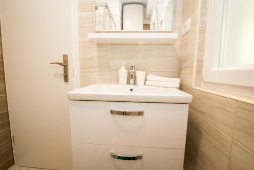 a white bathroom with a sink and a mirror at Apartment Spartion in Split
