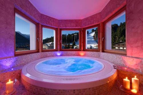 eine Whirlpool-Badewanne in einem Zimmer mit Fenstern in der Unterkunft Boutique Hotel Diana in Madonna di Campiglio