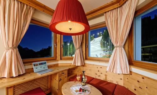 a room with windows and a table with a laptop at Boutique Hotel Diana in Madonna di Campiglio