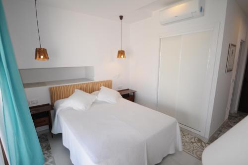 a bedroom with a white bed and a window at Chalet Torralba - Villa at Hotel Osiris in San Antonio