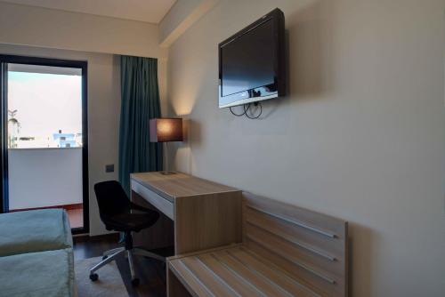 a hotel room with a desk and a tv on the wall at VIP Executive Zurique Hotel in Lisbon