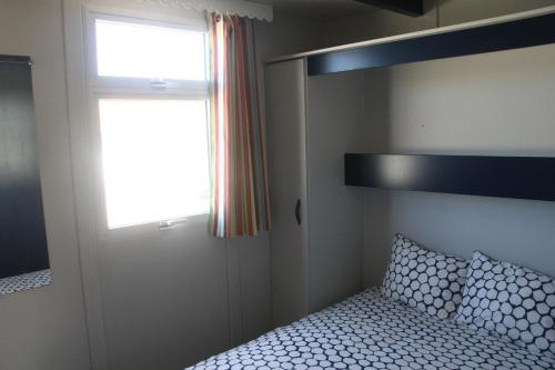 a small bedroom with a bed and a window at Torreira Camping & Bungalows in Torreira