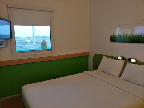 a bedroom with a white bed and a window at Cordia Hotel Surabaya Airport - Hotel Dalam Bandara in Sidoarjo