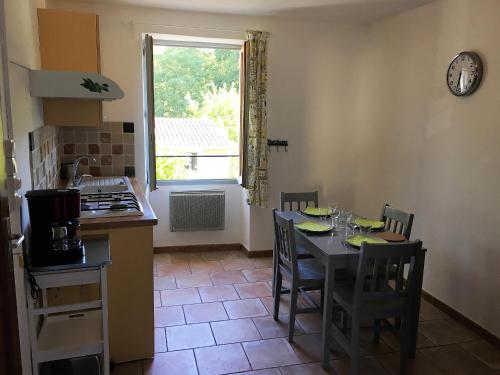 une cuisine avec une table et des chaises ainsi qu'une fenêtre dans l'établissement Appartement Paisible, à Fontaine-de-Vaucluse