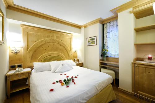 a bedroom with a white bed with flowers on it at Boutique Hotel Diana in Madonna di Campiglio