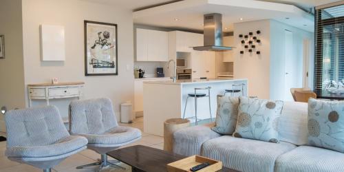 a living room with a couch and chairs and a kitchen at The Glen Apartments in Cape Town