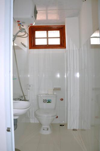 a white bathroom with a toilet and a sink at Ngoc Tung Mini Hotel in Hue