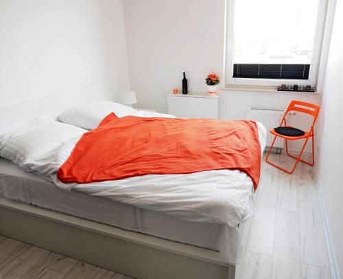 łóżko z pomarańczowym kocem w pokoju w obiekcie Sunshine Rooms w Gdańsku