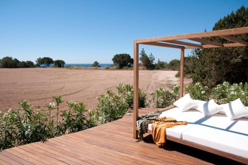 a bed on a wooden deck with a field in the background at Villas Paraíso de los Pinos in Sant Francesc Xavier