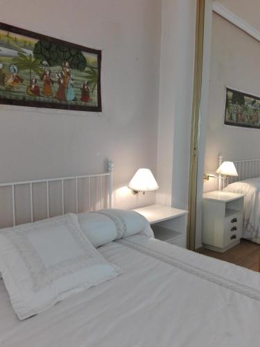 a white bedroom with a bed and a table with lamps at Casa Bellavista in Segovia