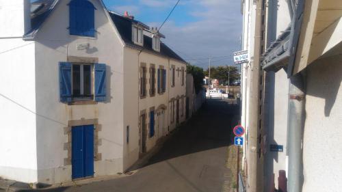 an alley with a building with blue windows and a street at Appartement Rue Haute des Bains in Le Croisic