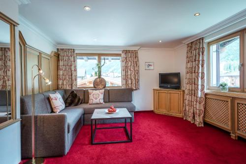 a living room with a couch and a tv at Hotel Auenhof in Lech am Arlberg