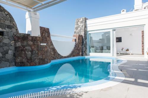 una piscina en una casa con una pared de piedra en Secret Earth Villas - Santorini, en Kamari