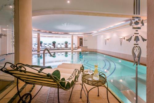 - une piscine avec 2 chaises et une table dans l'établissement Hotel Auenhof, à Lech am Arlberg