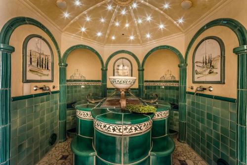 a bathroom with green tiled walls and a large tub at Hotel Auenhof in Lech am Arlberg