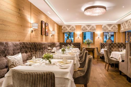 un ristorante con tavoli e sedie bianchi e pareti in legno di Hotel Auenhof a Lech am Arlberg